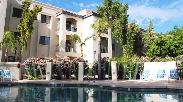 Pool surrounded by landscaped grounds and apt bldg at Fellowship Square Phoenix Independent Living community