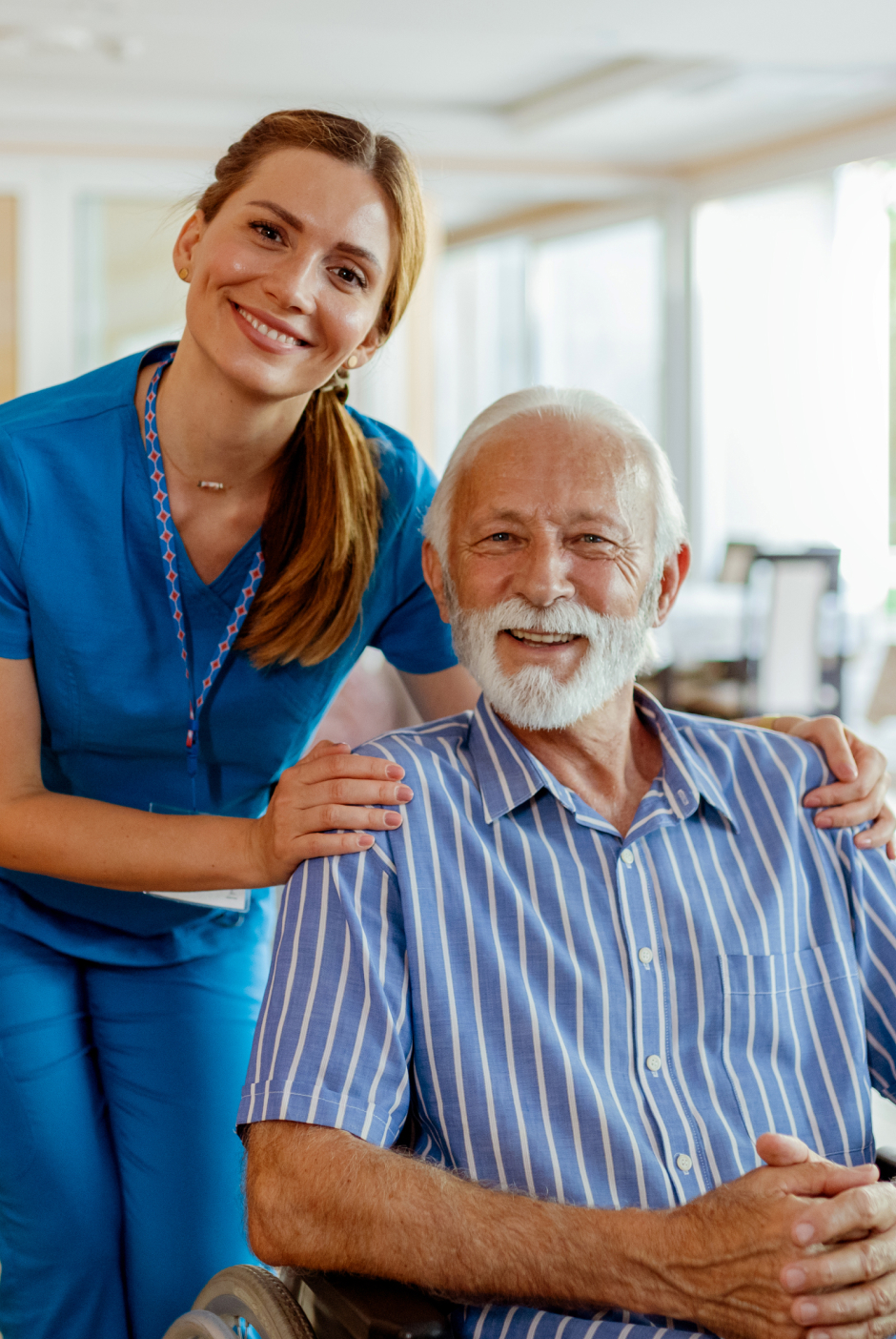 Senior man seated in wheelchair with caregiver standing beside him at The Oasis Assisted Living community