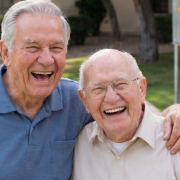 Two senior men smiling and laughing together outdoors at Fellowship Square community
